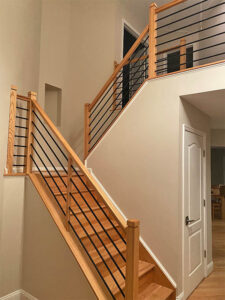 Light finished wood staircase with metal horizontal bar railing, installed by Darby Stair Renovations.