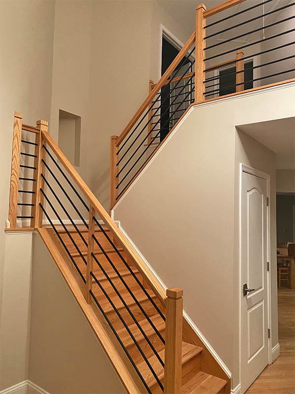 Light finished wood staircase with metal horizontal bar railing, installed by Darby Stair Renovations.
