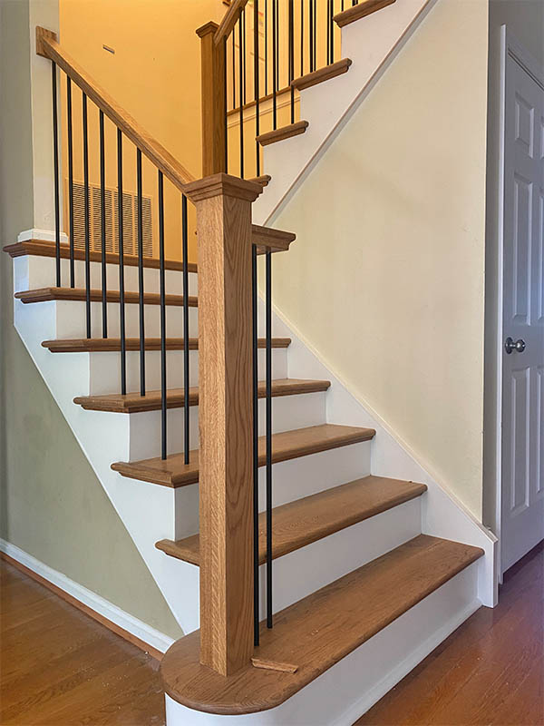 New staircase renovation with light stained wood and dark metal balusters.